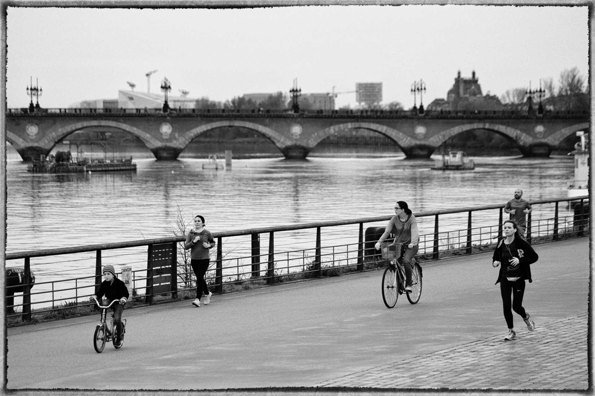 Des personnes courent ou font du vélo en bord de Garonne.